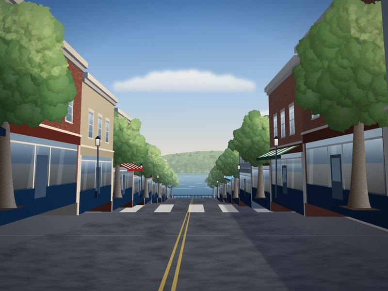 Main street of a small river town lined with two-story brick storefronts and street trees, sloping down to a glimpse of the river and wooded far bank